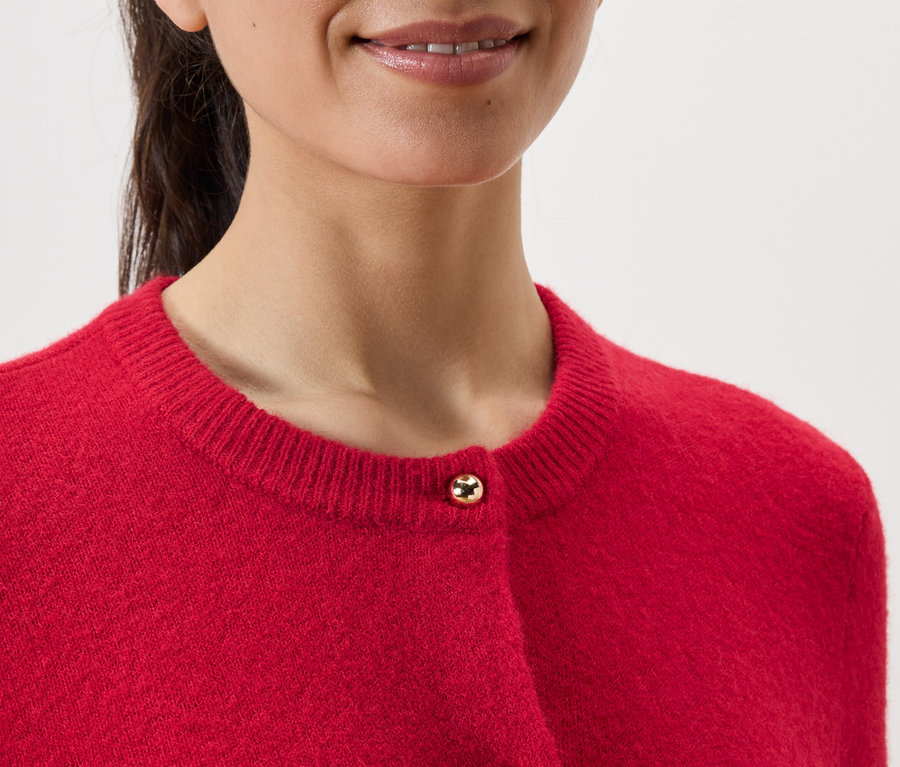 Közelkép egy nőt ábrázol, aki piros kardigánt visel.