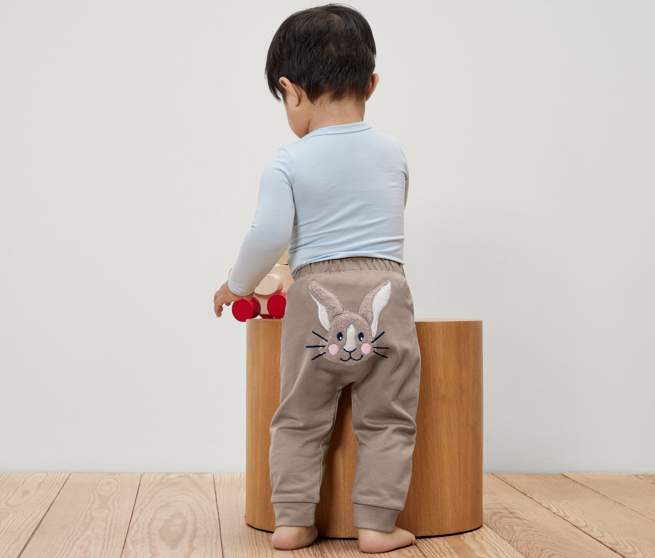 Egy kisgyerek áll háttal, nyuszis kisgyerek szabadidőnadrágot visel.