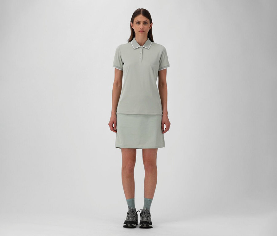 Nő CMP női szabadidős szoknyában és pisztácia CMP női rugalmas piké pólóingben, szürke zoknival és túracipővel.