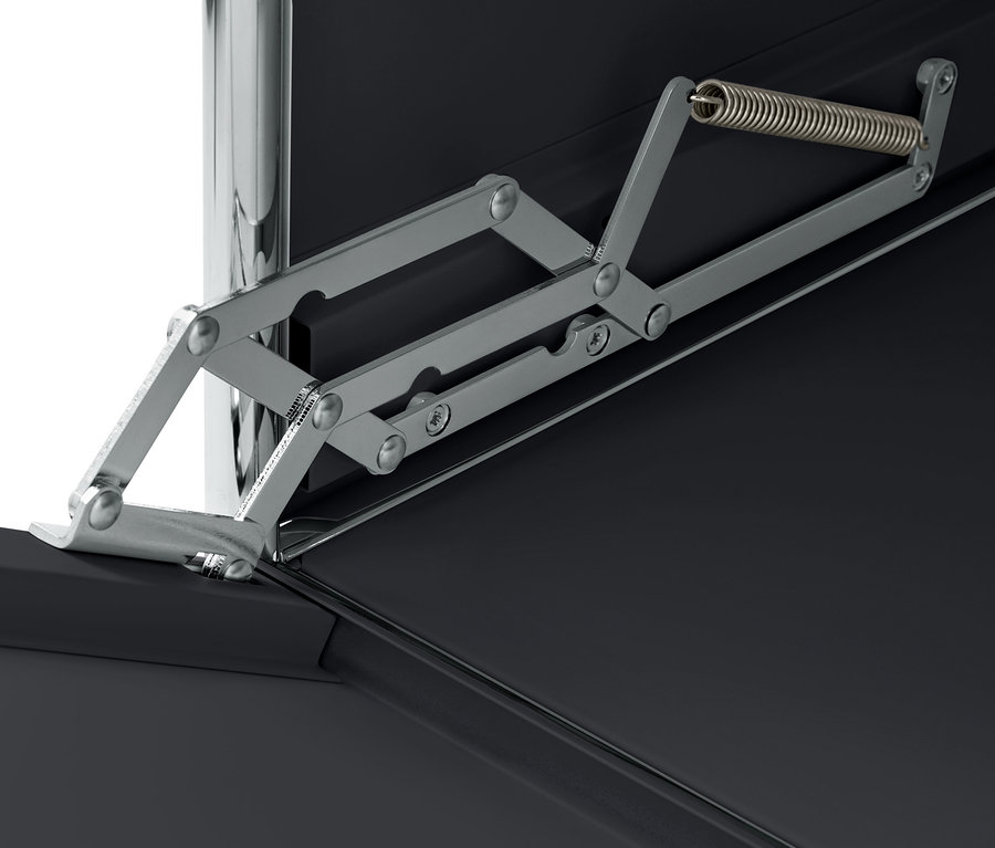 A fekete, fém, görgős, 1 ajtós tároló zsanérmegoldásának részlete.