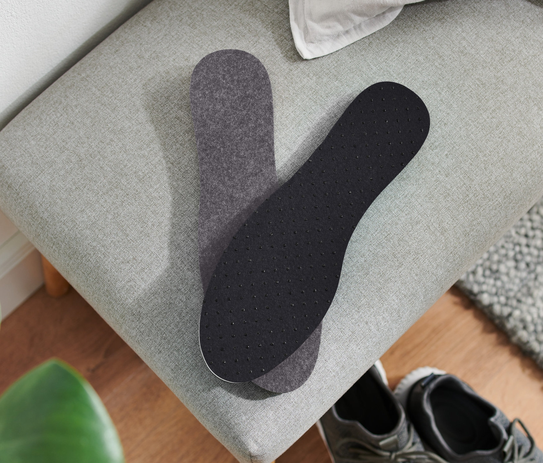 Két termo talpbetét fekszik egy szürke padon egy pár szürke cipő mellett.