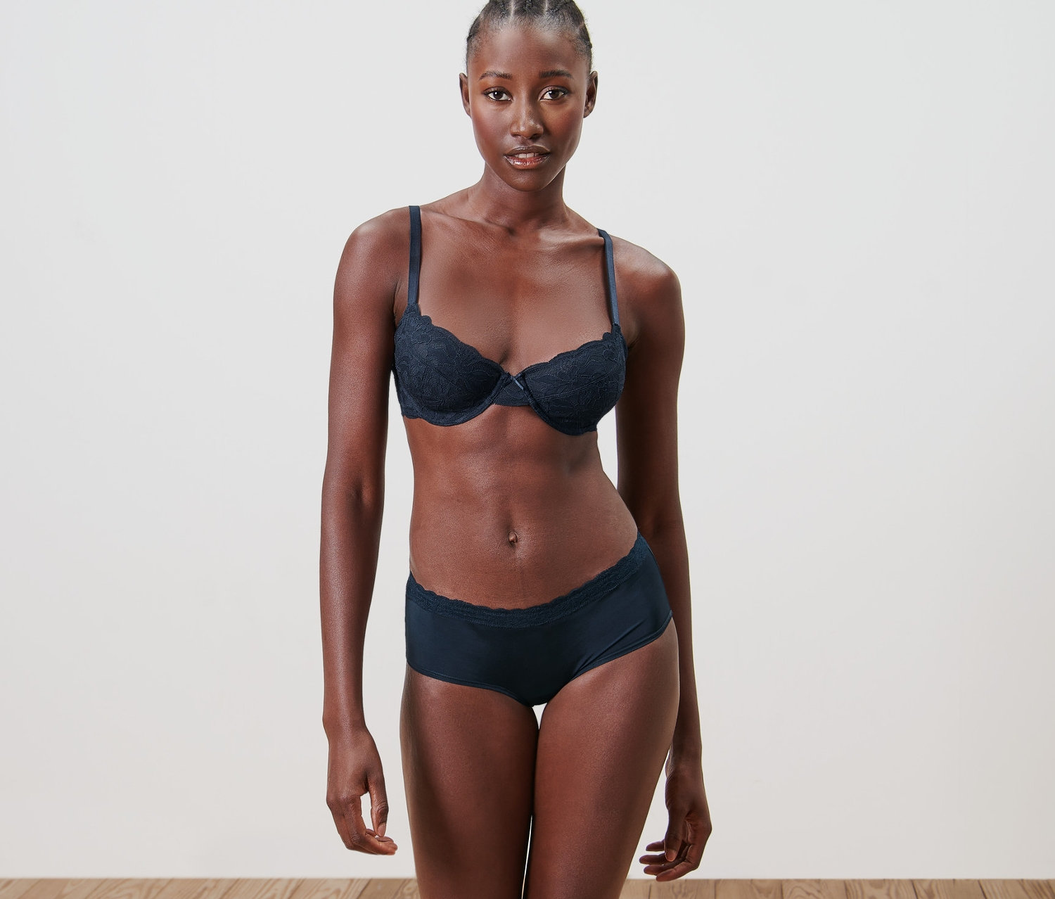 Fekete bőrű nő fehérneműben pózol. Melltartót és 5 db női magas derekú alsót visel, microtouch, csipkés, sötétkék.