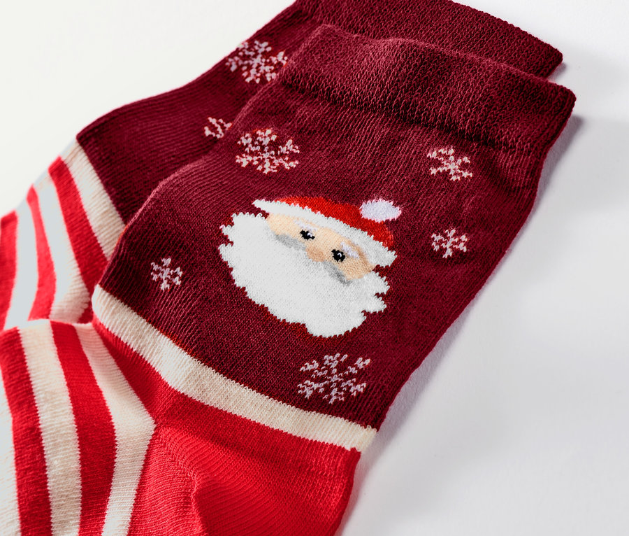 Egy pár bordó karácsonyi zokni részlete Mikulás és hópehely mintákkal.