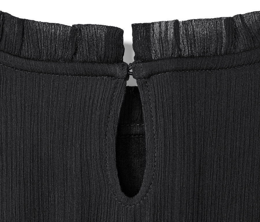 Egy fekete lány sifon ruha részlete fodros nyakkal és könnycsepp alakú kivágással.