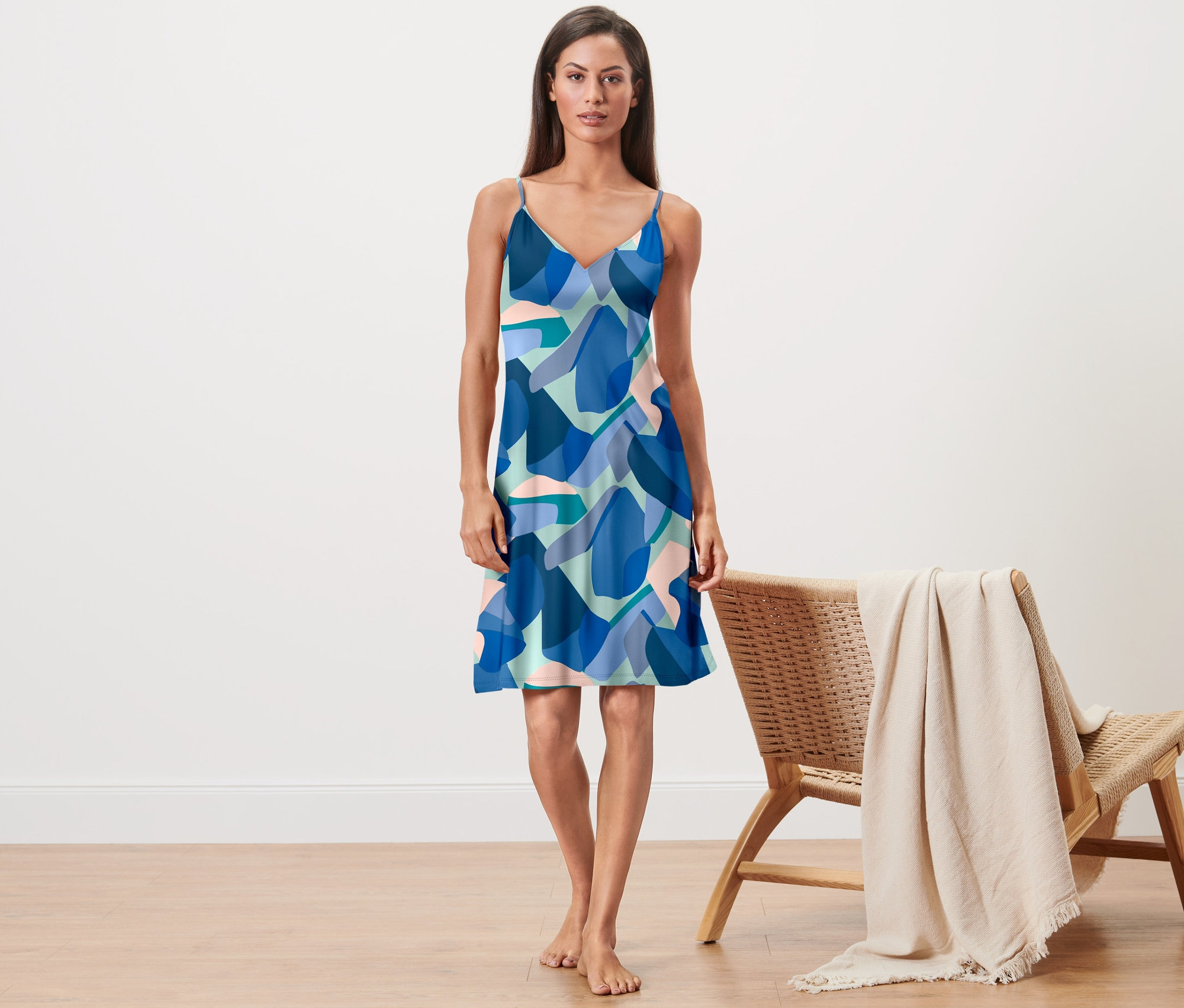 Egy nő áll mezítláb és egy kék mintás pántos hálóinget visel.