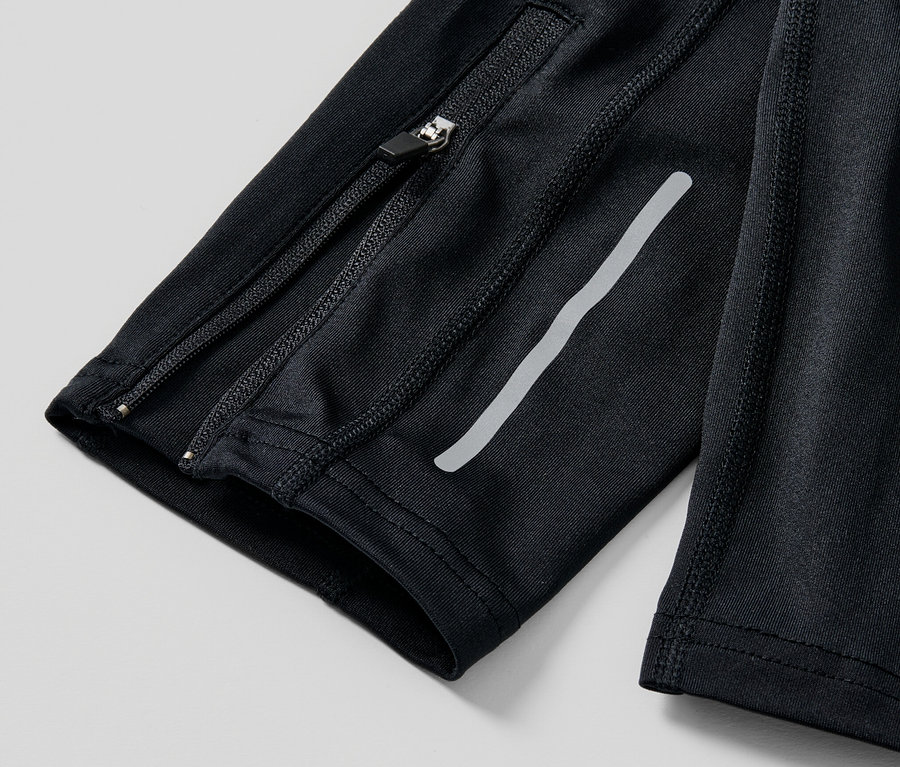 Egy fekete férfi futónadrág részlete cipzárral és fényvisszaverő csíkkal.