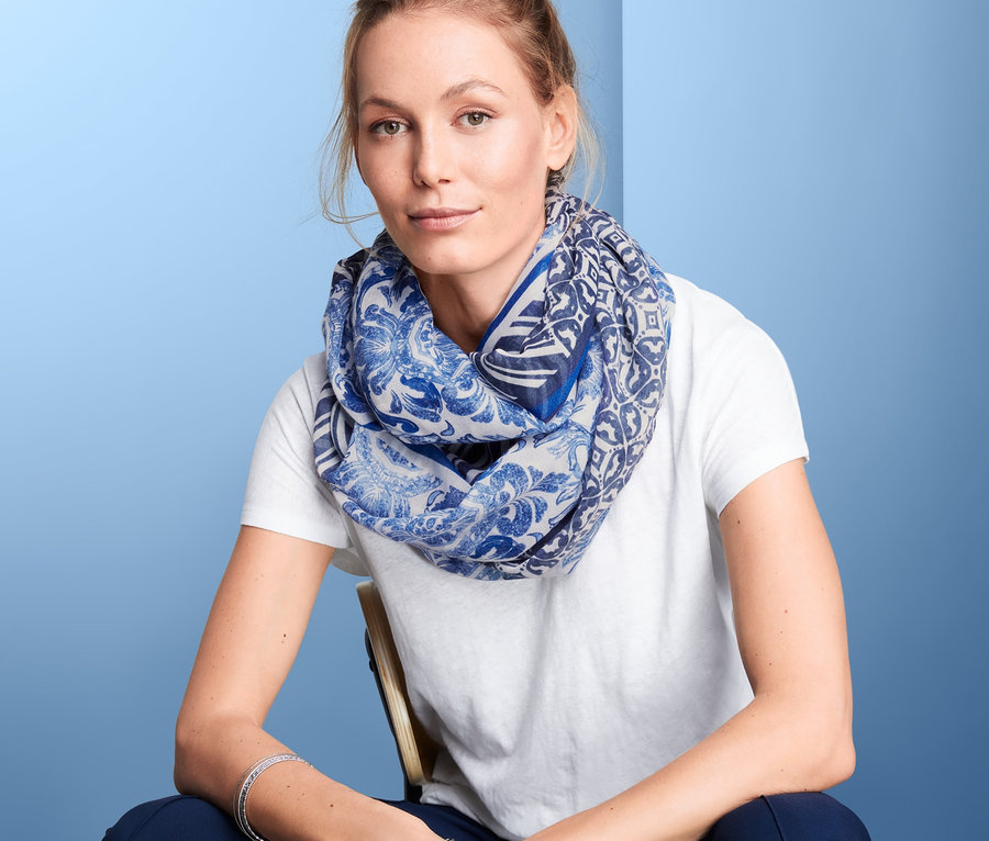 Nő ül egy széken, és mintás, kék női csősálat visel.