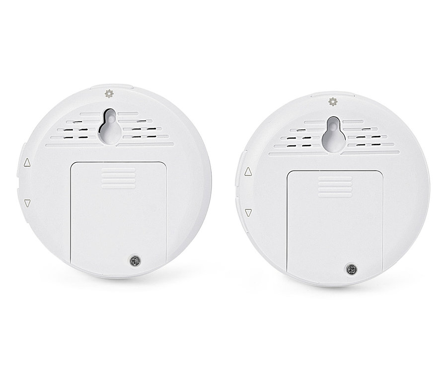 Két fehér, kerek érzékelő fali tartókkal és elemtartó fedelekkel.