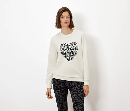 Nő visel fehér pulóvert állatmintás szívvel és állatmintás leggingset.