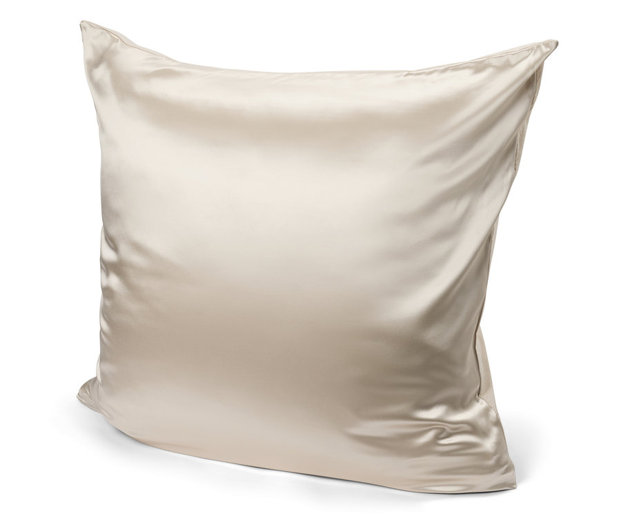 Egy bézs színű szatén párna fehér háttérrel.