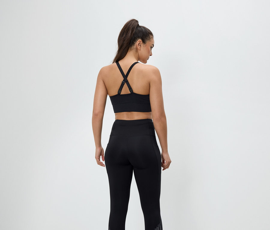 Hátulról látható egy fekete sportruházatot viselő nő, sportmelltartót és leggingset visel.