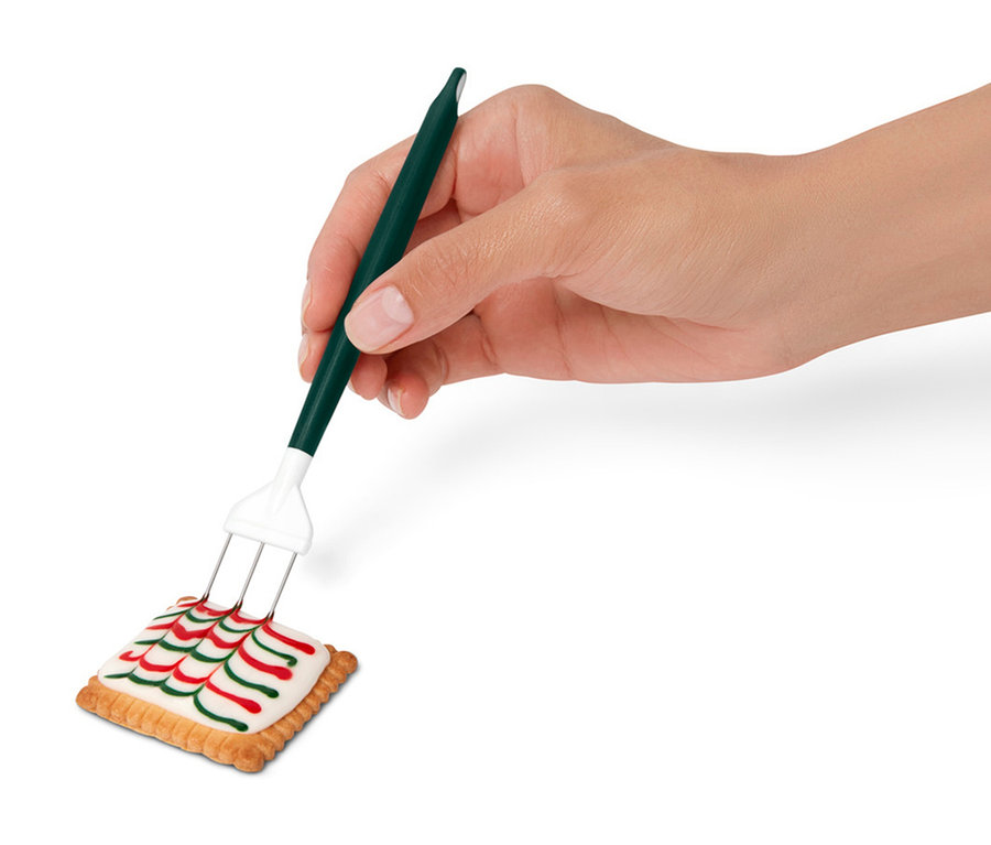 Egy kéz díszít egy sütit egy dekorációs eszközzel.