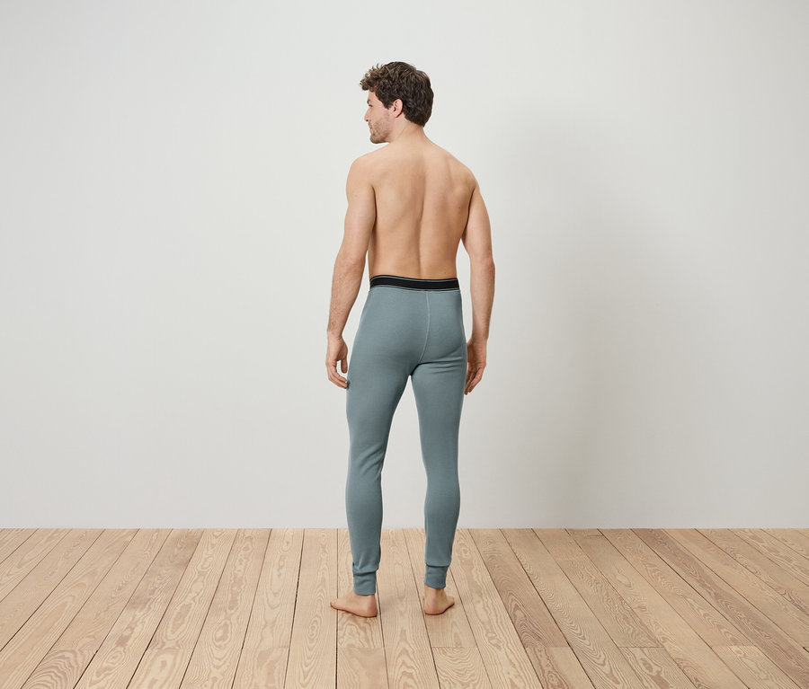 A férfi háttal áll a kamerának, szürke thermo alsóruházatot visel.