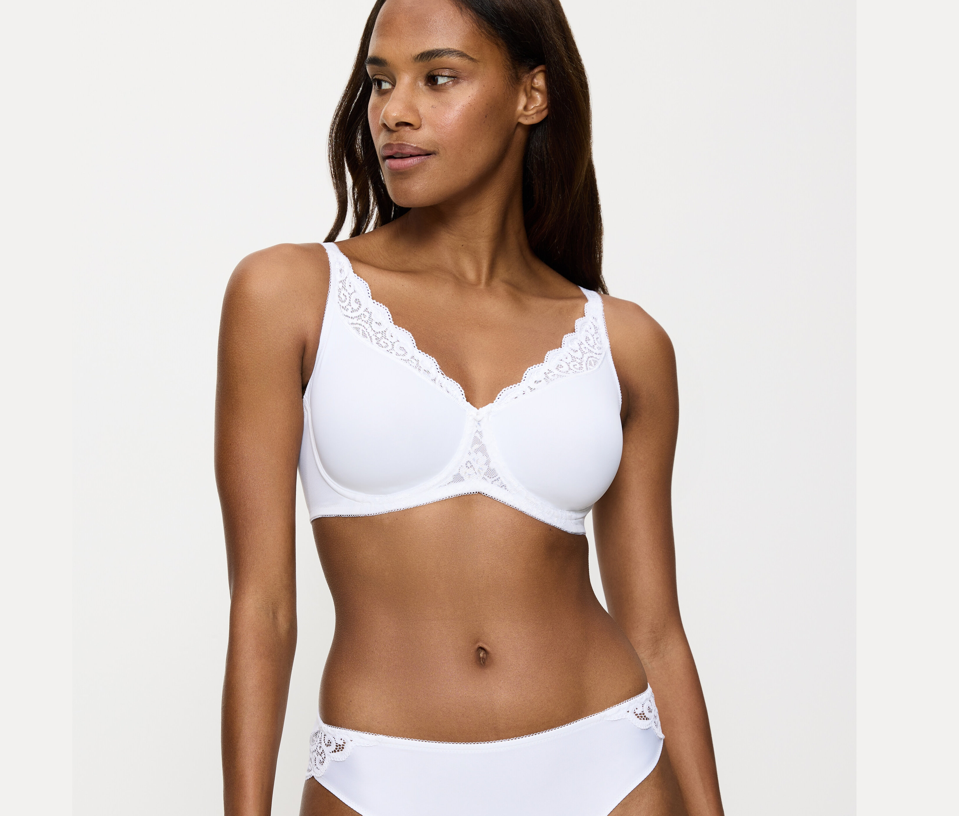Nő visel fehér Triumph Amourette kicsinyítő melltartót.