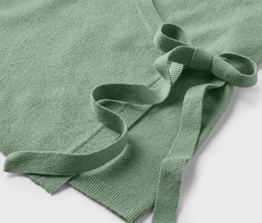 Egy világoszöld, megkötős kardigán részlete.