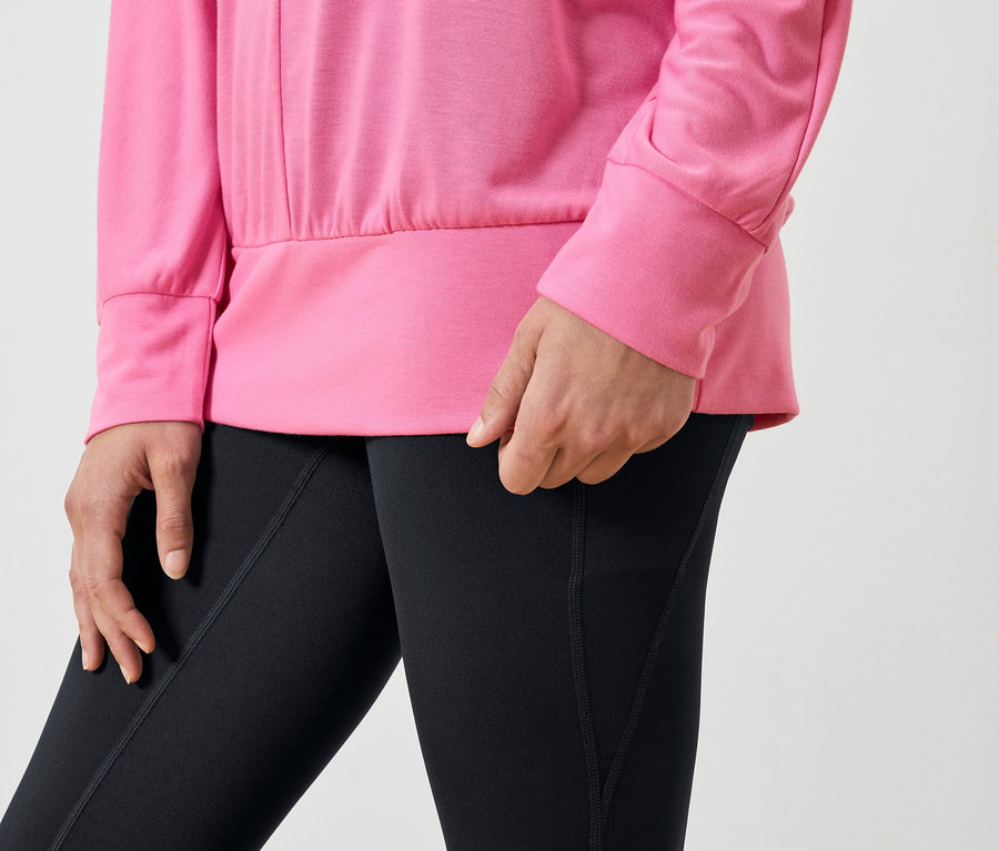 Egy nő részlete rózsaszín pulóverben és fekete leggingsben.