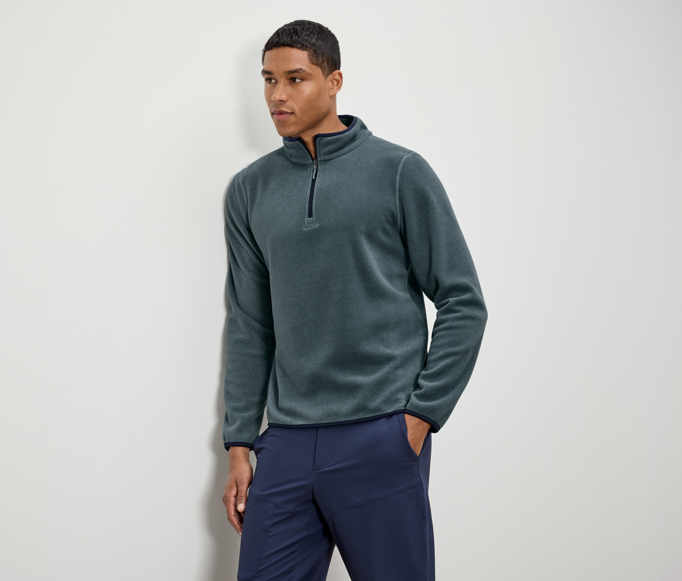 Férfi visel zöld fleece pulóvert sötétkék nadrággal.