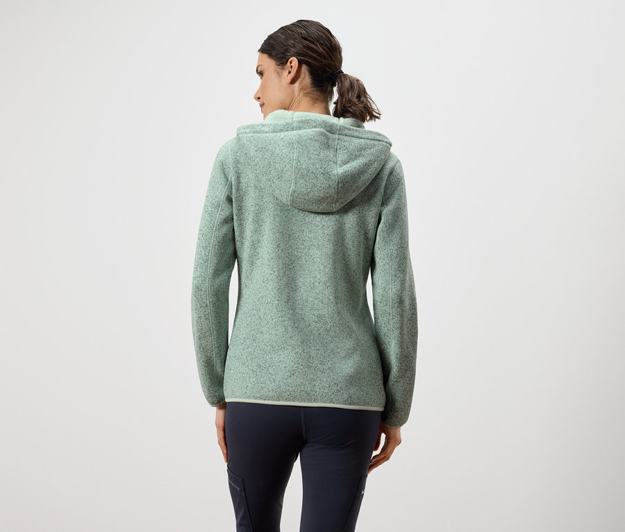 Hátulról látható egy nő zöld kapucnis pulóverben és sötétkék nadrágban.