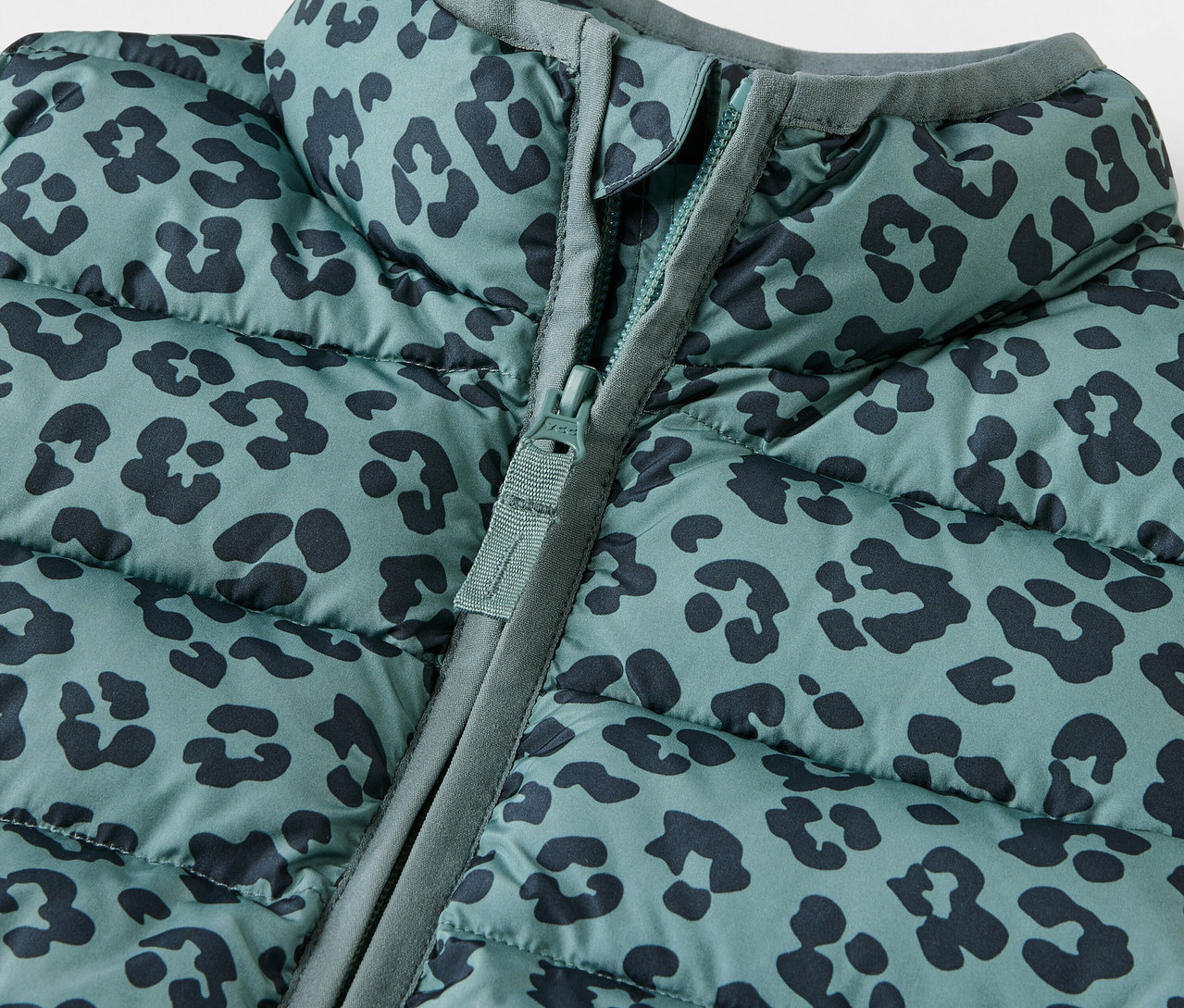 Közelkép egy állatmintás, cipzáras, steppelt gyerekmellényről.