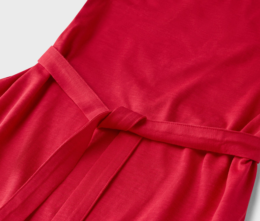 Egy megkötött övvel ellátott vörös ruha közeli képe.