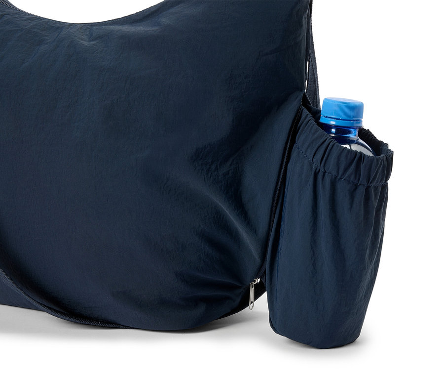 Egy sötétkék táska közeli képe, oldalán egy vizes palackkal.