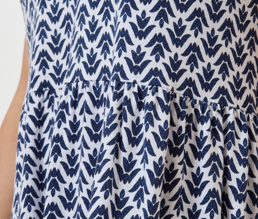 Közeli kép egy fehér ruháról kék levélmintával.