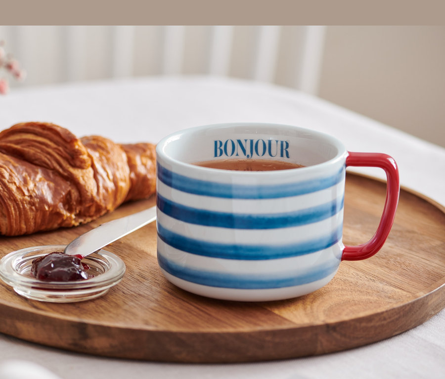 A fa tálcán egy croissant, lekvár és egy Bonjour feliratú porcelán bögre található.