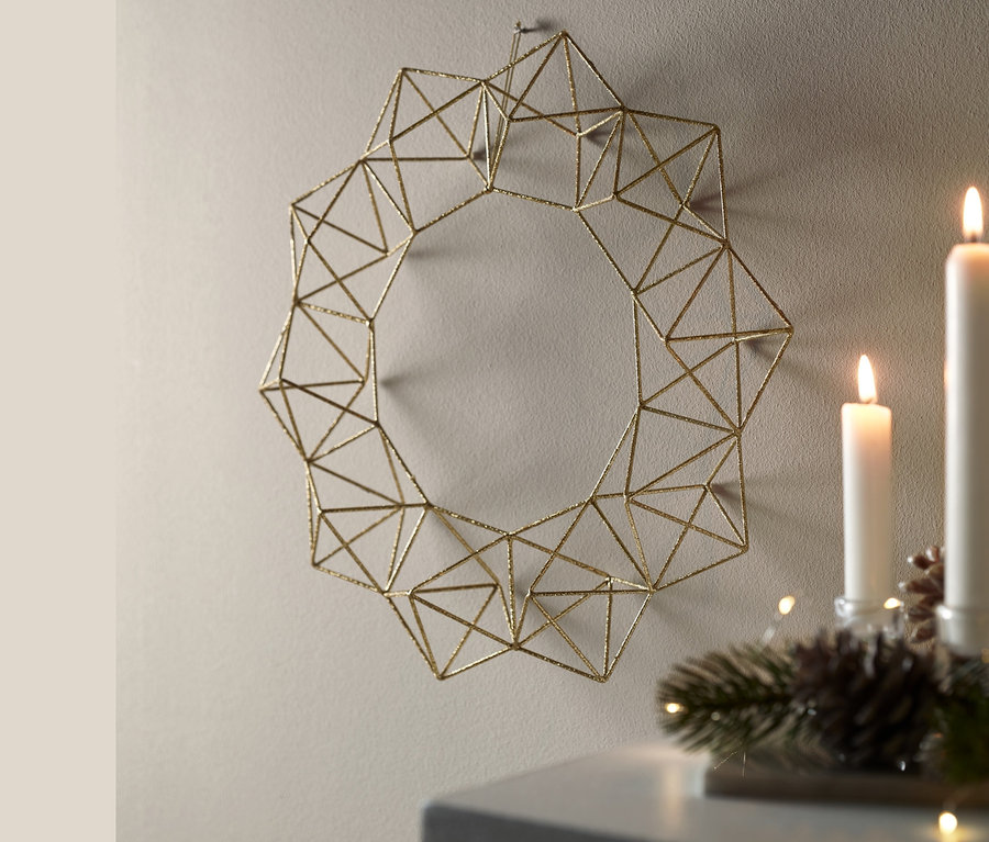 Fém díszkoszorú, arany színben a falon.