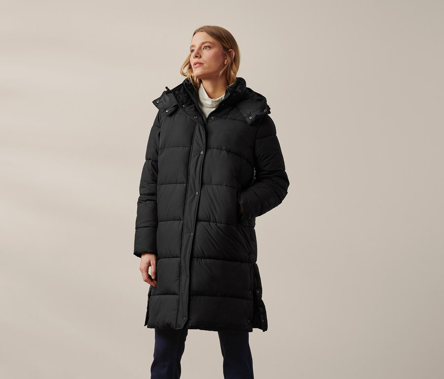 Nő visel fekete, steppelt kapucnis kabátot.