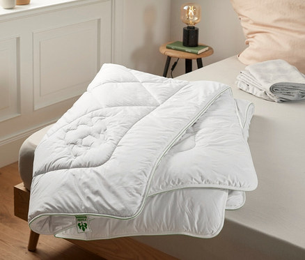 Az ágyon egy fehér irisette® greenline teveszőr dupla paplan fekszik.