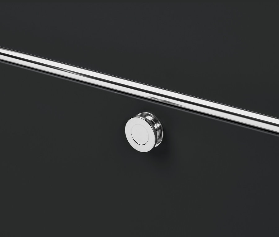 Közeli kép egy fekete »CN3« komódról négy lenyíló ajtóval, krómozott fogantyúval és kerek gombbal.