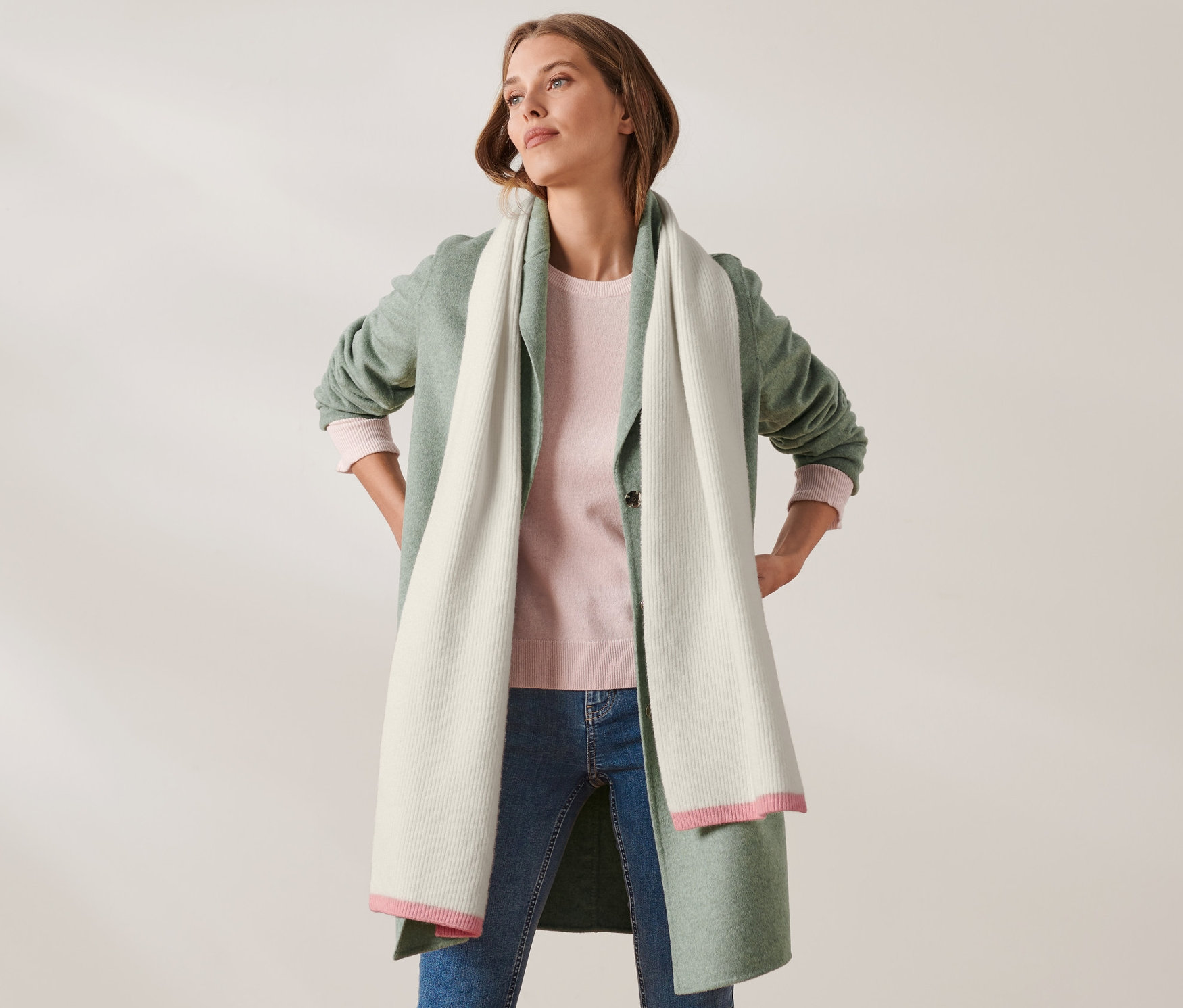 Egy nő csípőre tett kézzel pózol, és kötött, gyapjú tartalmú sálat visel.