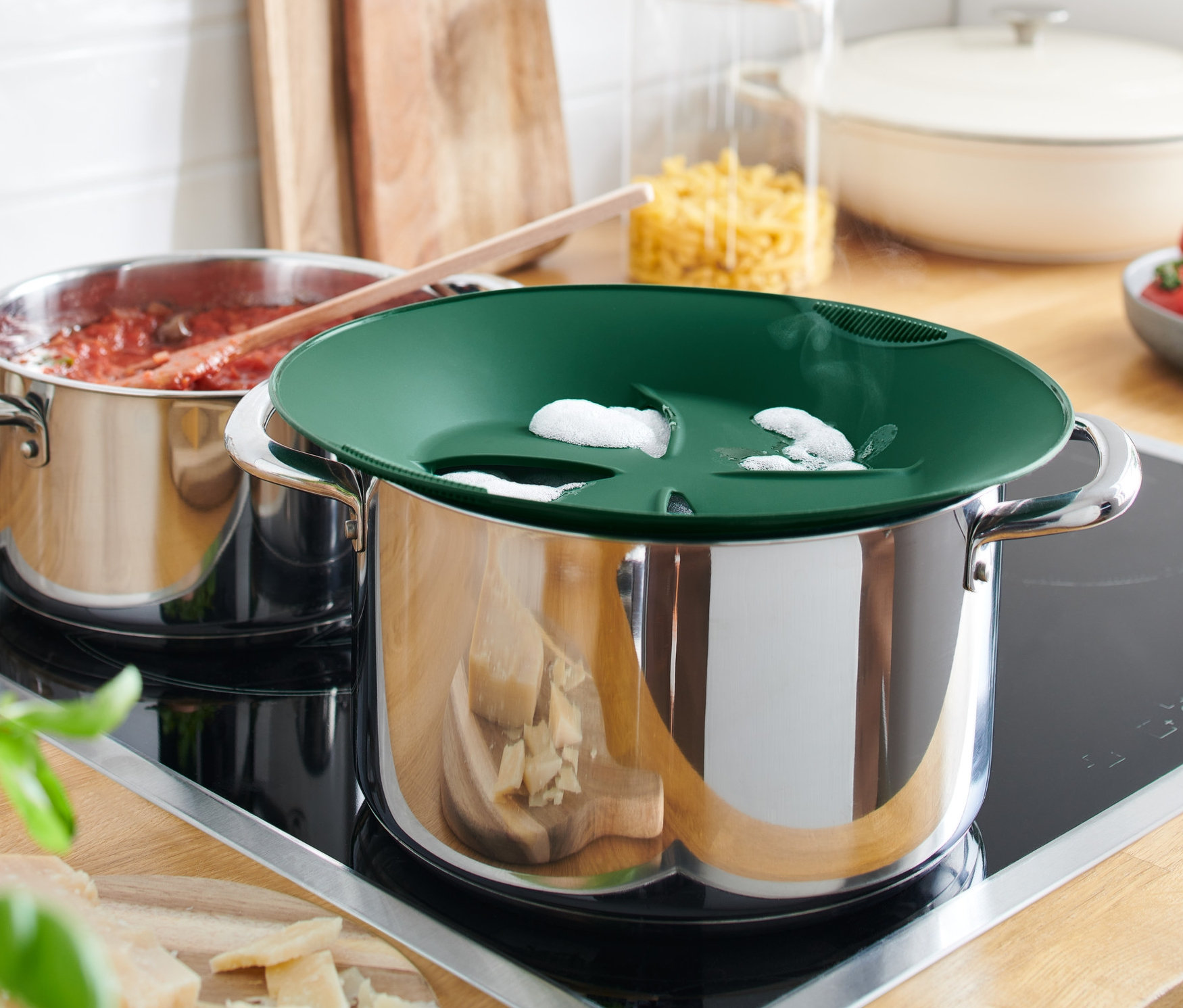 Két edény áll a főzőlapon, az egyiken szilikon kifutásgátló van, a másikon paradicsomszósz.