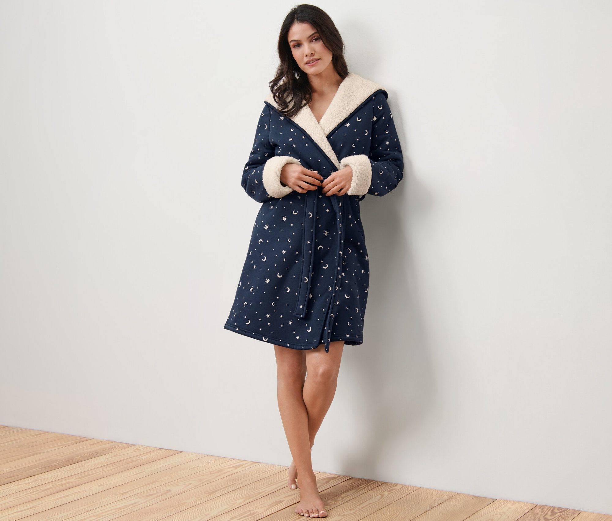 Nő pózol a stúdióban, csillagmintás, plüss bélésű női köntöst visel.