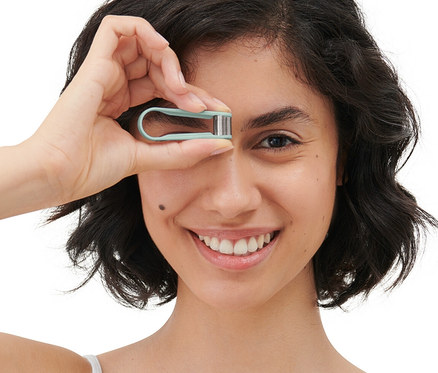 Nő tart egy manuális mini arcepilátort a szeme előtt.