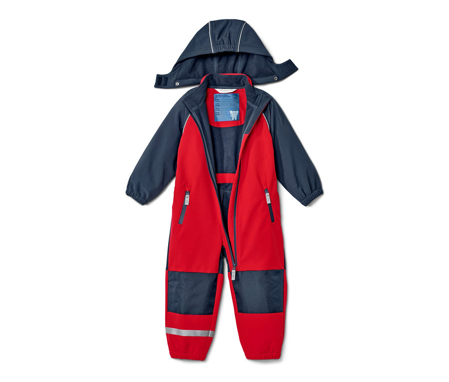 Nyitott, piros-kék gyermek softshell kezeslábas kapucnival a hátán fekszik.