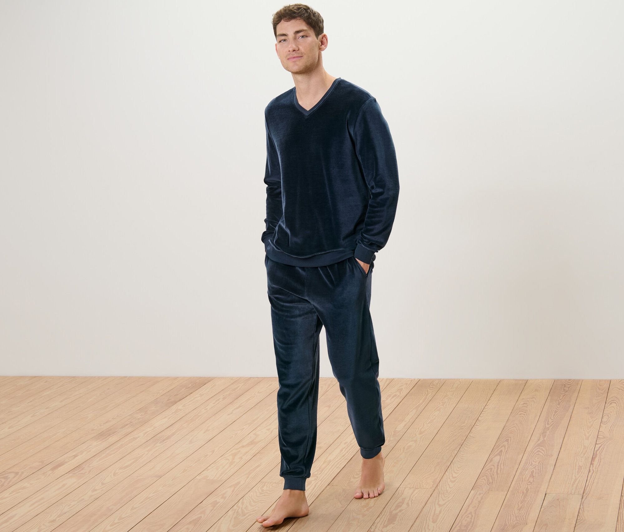 Egy férfi áll mezítláb, plüsspizsamában.