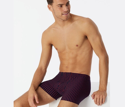 Férfi ül és piros SCHIESSER biopamut boxeralsót visel.