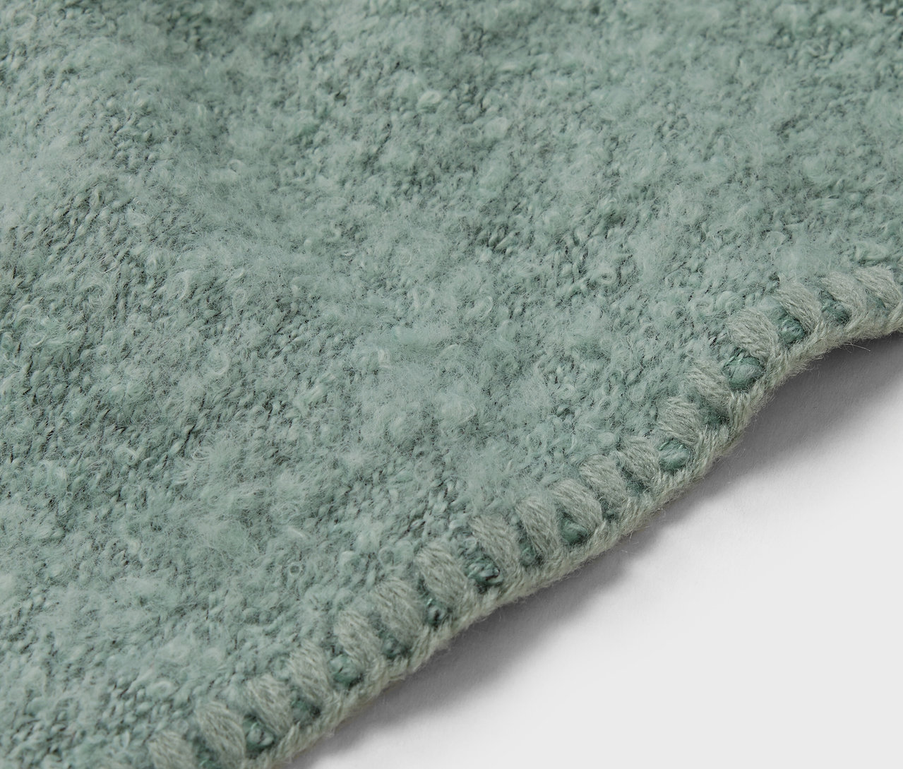 Egy világoszöld szőnyeg részlete díszszegéllyel.