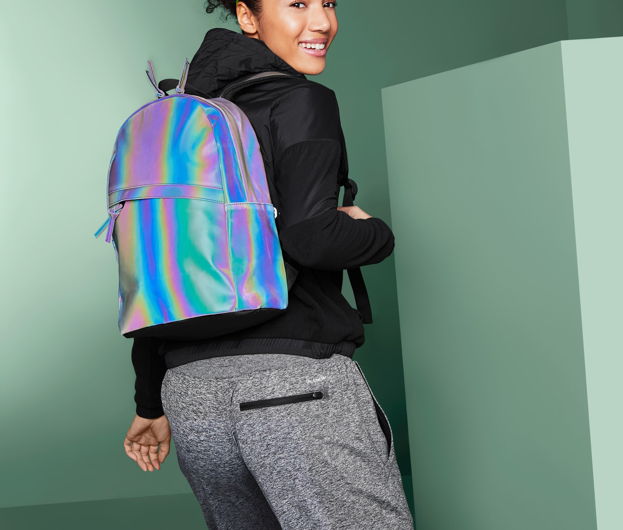 Nő néz a válla fölött, fényvisszaverős hátizsákot visel.