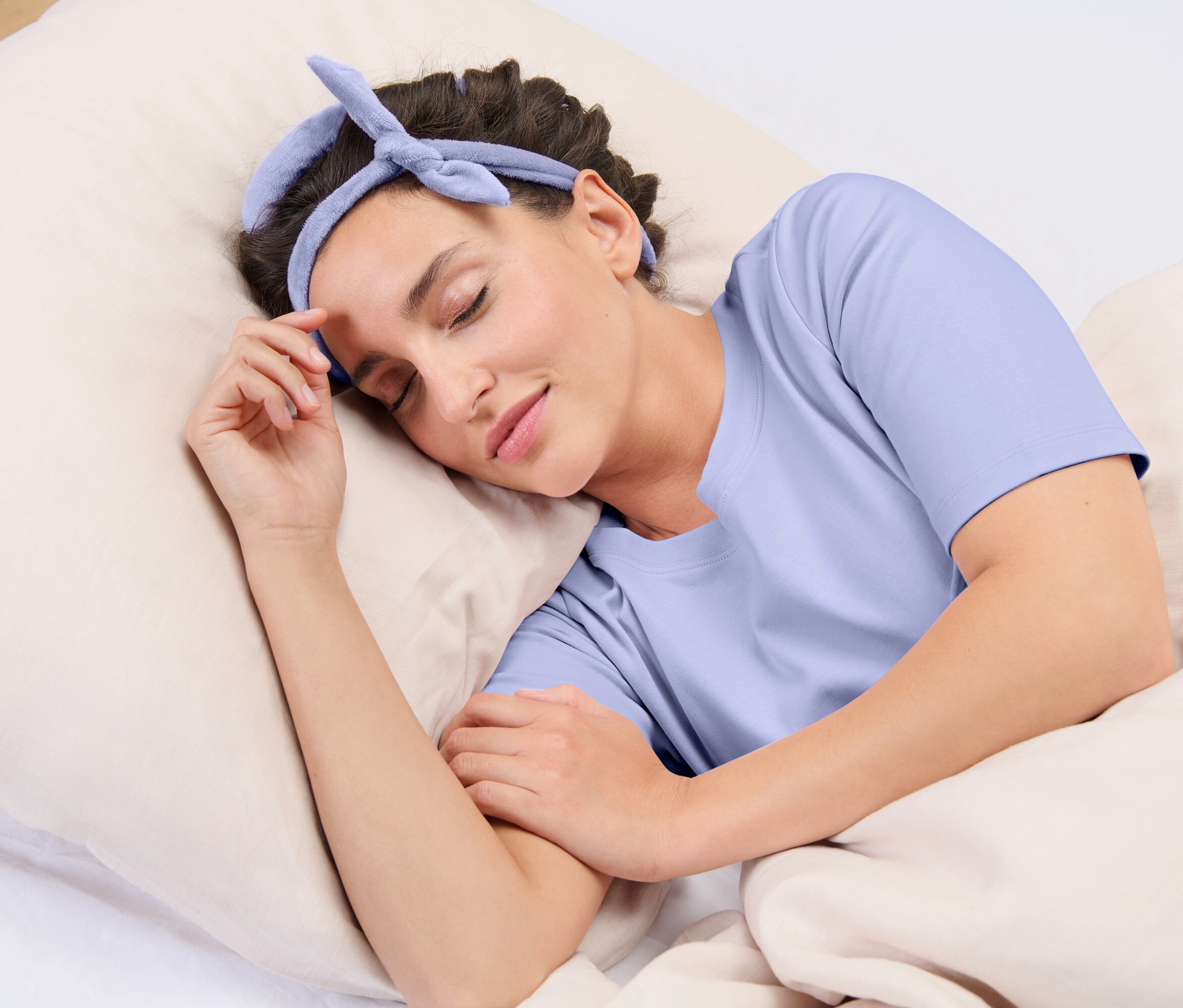 Egy nő alszik egy párnán, kék fejpánttal a fején.