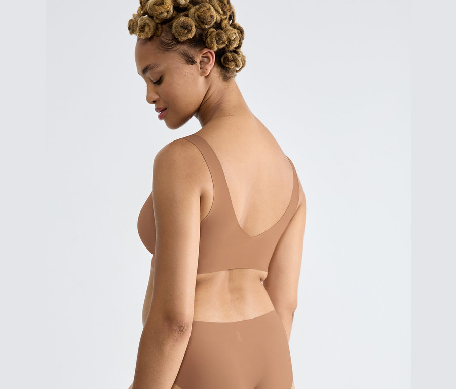 Nő visel egy nosztalgia barna sloggi ZERO Feel 2.0 Bralette melltartót.