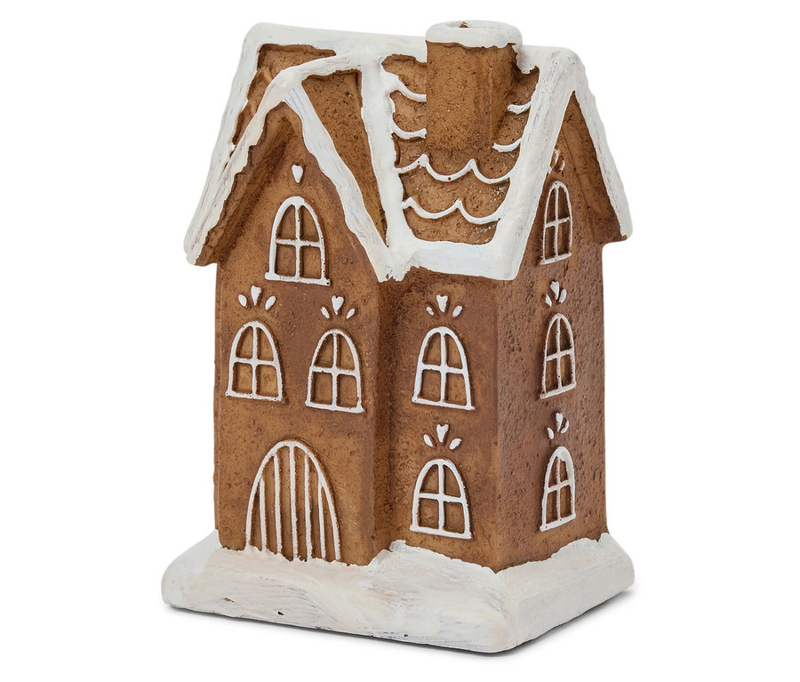 Közeli kép egy barna mézeskalács házikóról, fehér cukormázzal az ablakon és a tetőn.