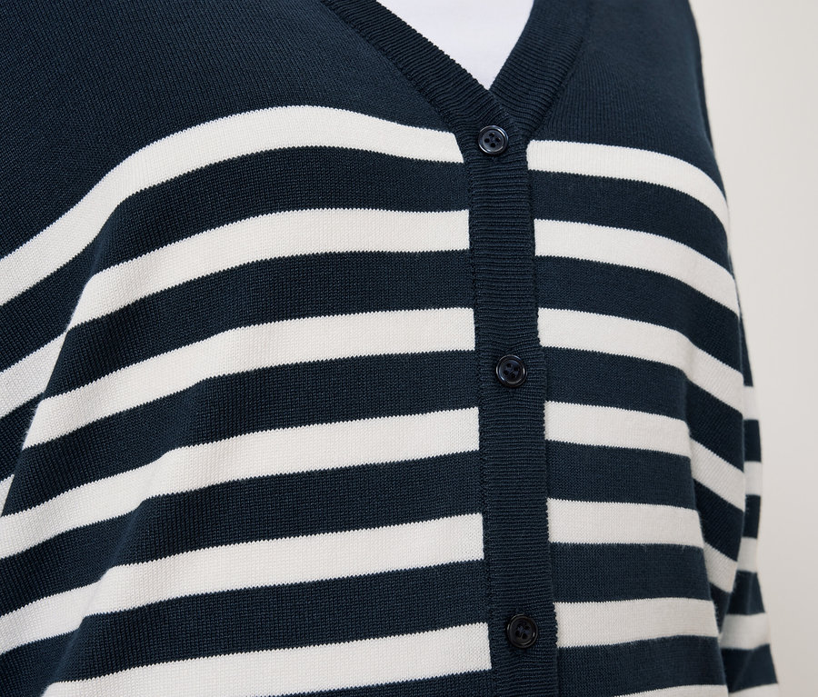 Egy kék, fehér csíkos, gombos kardigán részlete.