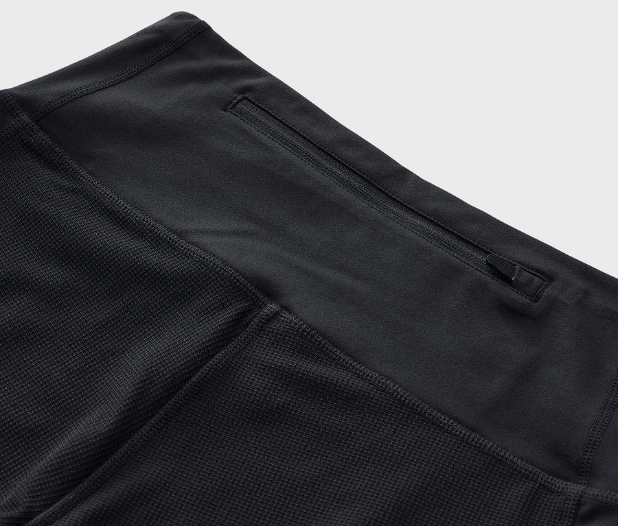 Egy fekete, 3/4-es női túranadrág részletfotója, cipzáras zsebbel a derékrészen.