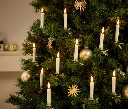 Egy karácsonyfa részlete, rajta díszek és gyertya alakú fények.