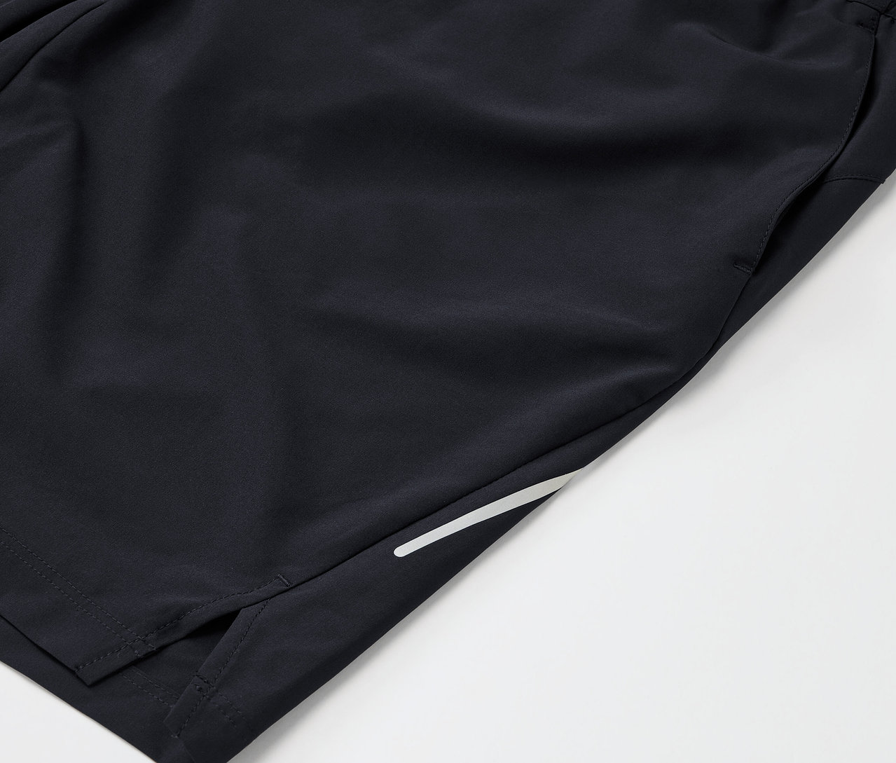 Fekete sport rövidnadrág részlete, zsebbel és fényvisszaverő csíkkal.