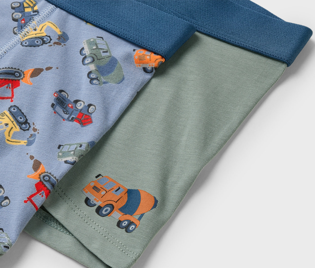 Két pár gyerek alsónadrág. Az egyik világoskék építőipari gépek mintával, a másik zöld betonkeverő képpel.