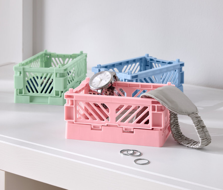 Három színes összecsukható doboz az asztalon, egy rózsaszín órával, egy kék és egy zöld.