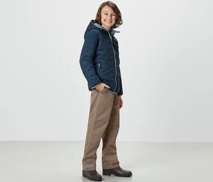 Egy fiú kabátban és Kinder-Regenhose oldalt áll.